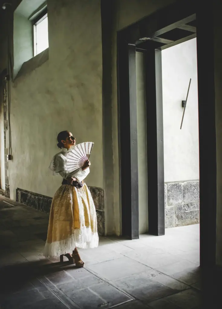 Woman holding a fan in a sunlit doorway